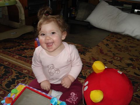 2000 Ford Crown Victoria - A happy baby girl sits on a patterned rug, surrounded by toys and a large white pillow in the background.