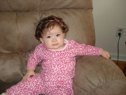 2000 Ford Crown Victoria - Baby girl in pink pajamas sits on a couch, looking at the camera.