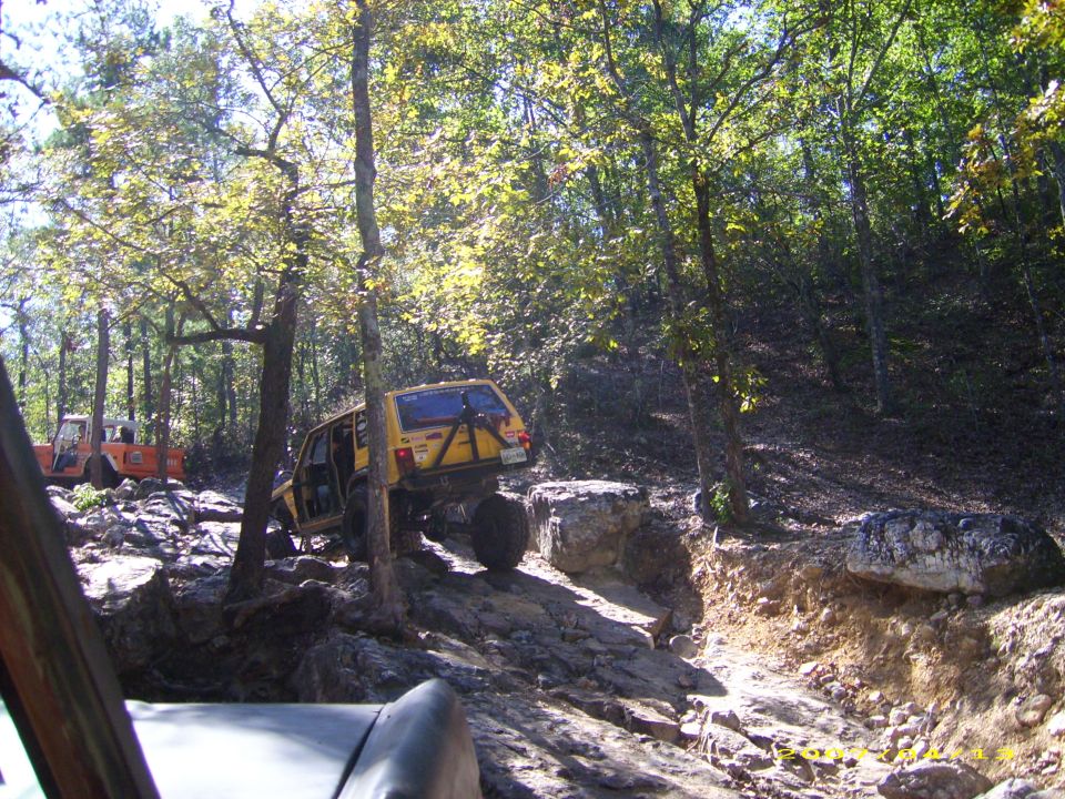 Yellow off-road SUV on rocky trail with another orange vehicle behind
