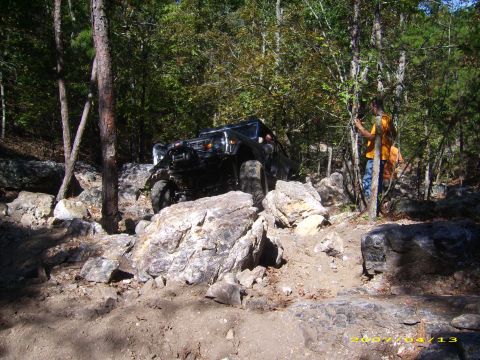 1978 Ford Bronco - Off-road vehicle tackling a challenging rocky path in a wooded area.