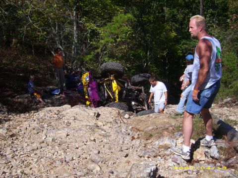 1978 Ford Bronco - An off-road vehicle has overturned on a rocky trail with several people observing the scene.