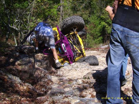 1978 Ford Bronco - An off-road vehicle is overturned on a rocky trail with people observing.
