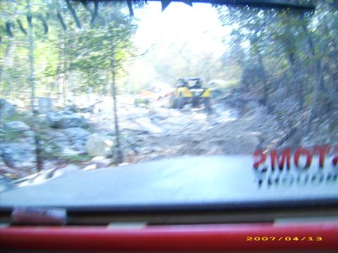 1978 Ford Bronco - An off-road vehicle navigates a challenging rocky path through a wooded area.