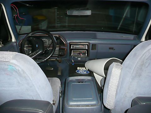 1991 Ford Bronco - The interior of a 1991 Ford Bronco shows blue cloth seats and a dashboard with a Ford logo on the center console.