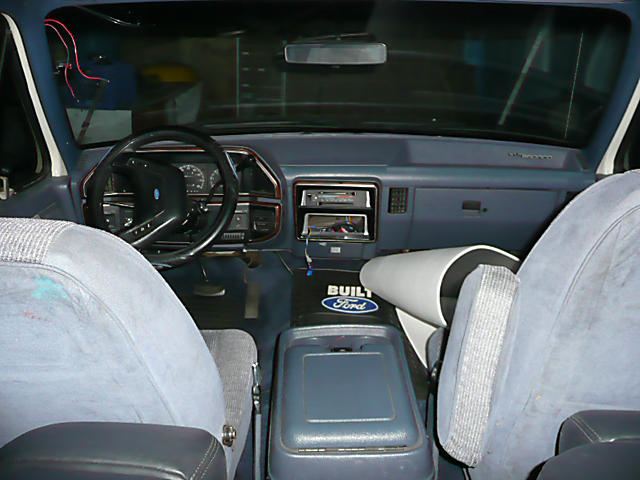 1991 Ford Bronco interior with blue cloth seats, dashboard, steering wheel, and center console with a Ford logo