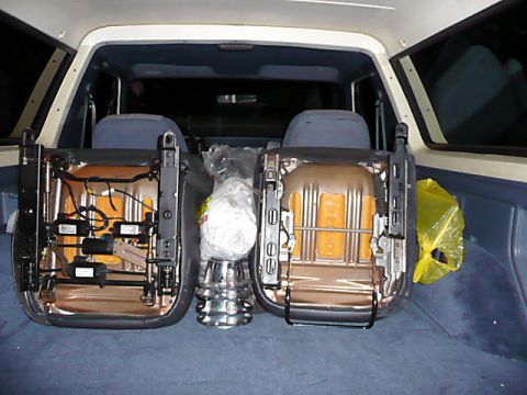 1991 Ford Bronco - The interior of a 1991 Ford Bronco is shown with the front seats removed, revealing the cargo area and some stored items.