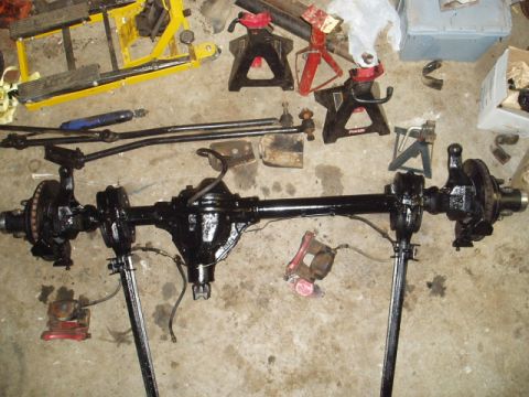 1980 Ford Bronco - A disassembled front axle assembly, likely for a truck or SUV, is laid out on the floor with various support tools.
