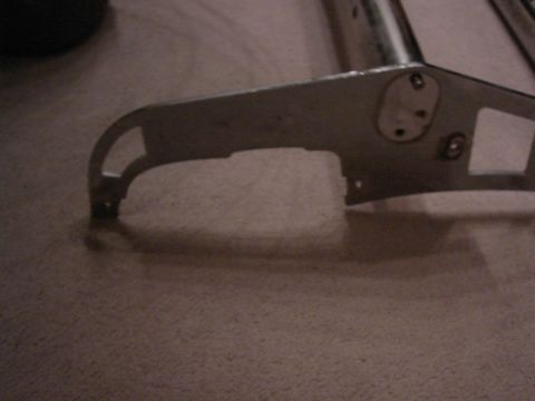 1987 Ford Bronco - Metal bracket with mounting holes shown on a carpeted floor.