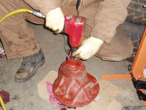 1980 Ford Bronco - A person is working on a red differential with an air-powered impact wrench in a garage setting.