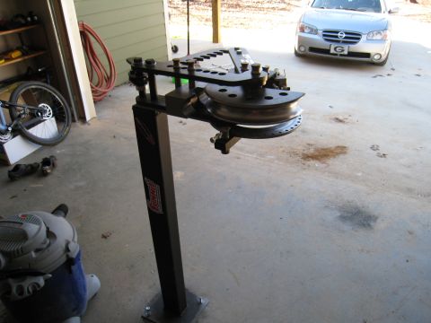 1996 Ford Bronco - A silver sedan is parked in a garage bay, with a tube bending machine in front of it.