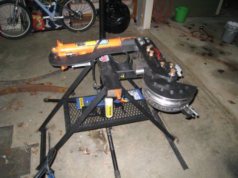 1996 Ford Bronco - A pipe bender is shown on a stand in a garage setting, with bicycles in the background.
