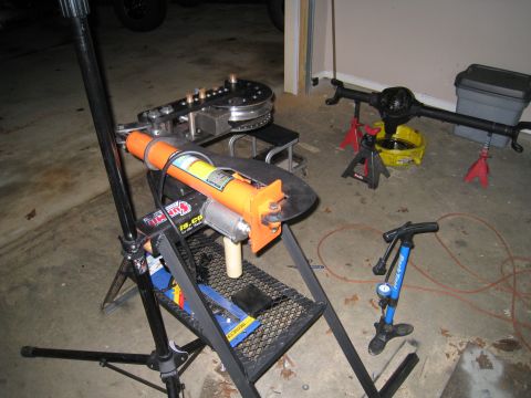 1996 Ford Bronco - Garage scene with a pipe bender and a rear axle assembly, tools for vehicle repair.