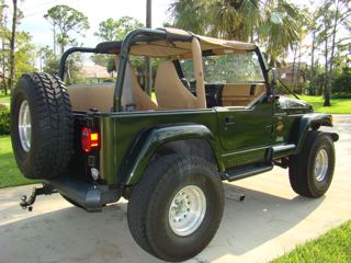 1998 Jeep Wrangler - 1998 Jeep Wrangler shown from the rear three-quarter angle. It has a tan soft top and interior.