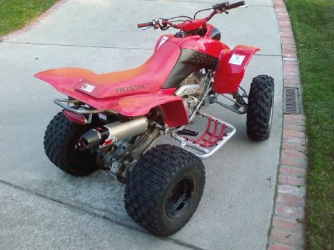 1995 Ford Bronco - A red Honda ATV is parked on a concrete driveway, viewed from the rear.