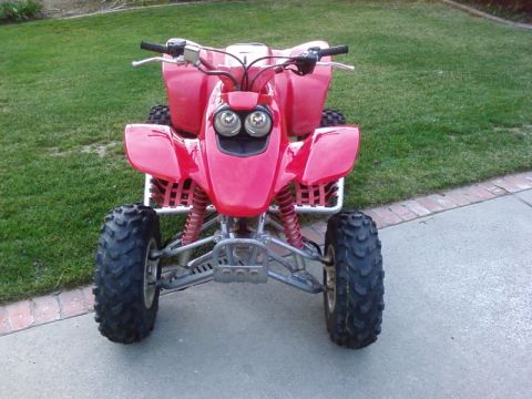 1995 Ford Bronco - Front view of a red all-terrain vehicle with knobby tires and dual headlights.
