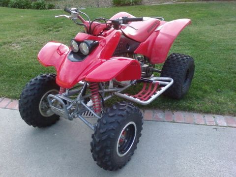 1995 Ford Bronco - A red ATV with knobby tires sits on a concrete surface in front of a grassy area.