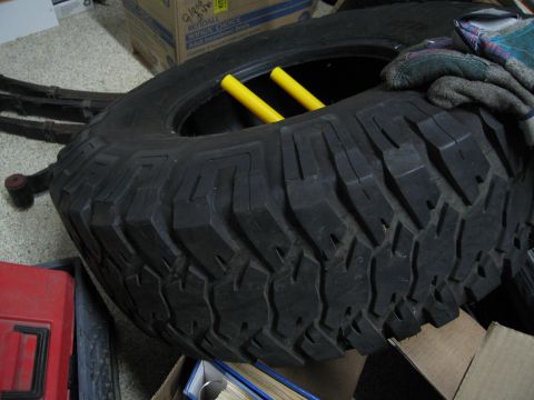 1986 Ford Bronco - A heavy-duty tire with a deep tread pattern is shown, with yellow bars inserted into the wheel.