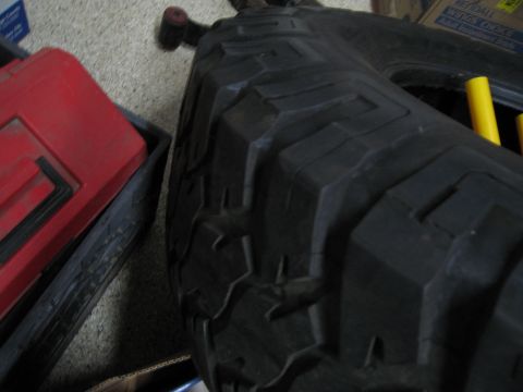 1986 Ford Bronco - A close-up view of a tire tread, with a red toolbox and yellow rods visible.