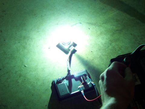 1993 Ford Probe - A hand connects wiring to a battery terminal, powering an automotive lighting component.