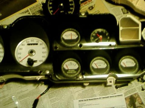 1976 Ford Ranchero - A collection of automotive gauges, some with white faces, are laid out on a surface covered with newspaper.
