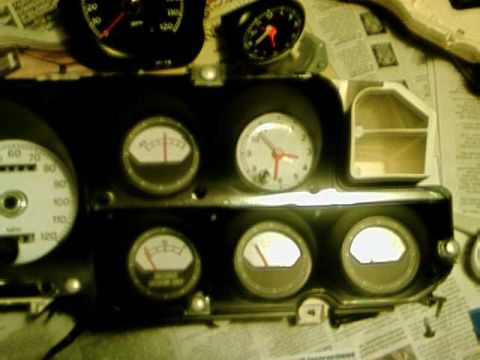 1976 Ford Ranchero - A close-up view of a set of white face gauges, likely from a vehicle's dashboard, with visible needles and numerical markings.