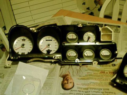 1976 Ford Ranchero - A collection of vehicle gauges, including a speedometer and tachometer, are displayed on a surface covered with newspapers.
