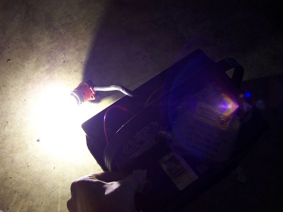 Hand holding flashlight on black box with wires and labels