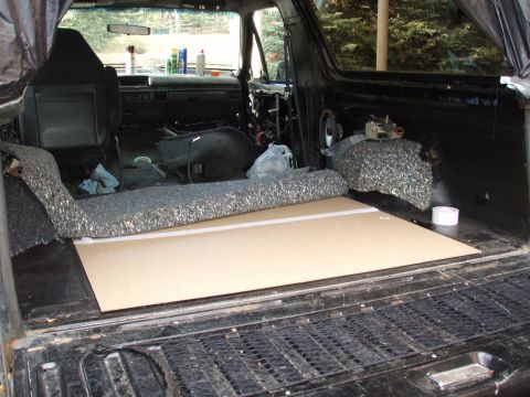 1992 Ford Bronco - The interior of a black SUV is being worked on, with sound deadening material and a new floor panel installed.