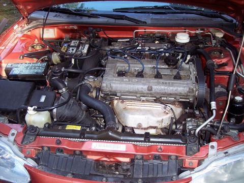 1995 Mitsubishi Eclipse - The engine bay of a red 1995 Mitsubishi Eclipse, showing the V6 engine and associated components.