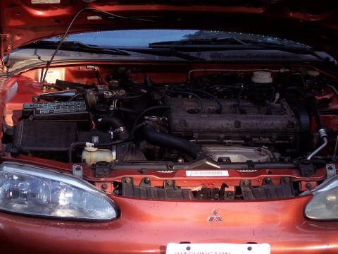 1995 Mitsubishi Eclipse - The engine bay of a 1995 Mitsubishi Eclipse is visible with the hood raised, revealing the engine and front end.