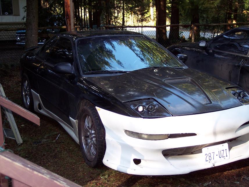 Front view of a modified black sports car with a white body kit and aftermarket hood