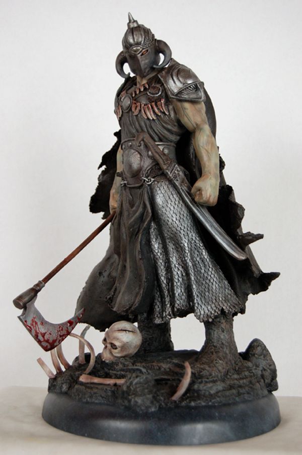 Statue of a barbarian warrior with helmet, axe, and skull at base