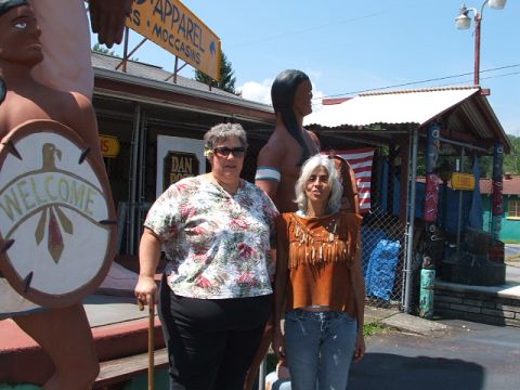 1966 Ford Ranchero - A scene depicts two women posing in front of a roadside attraction with Native American-themed statues and a store.