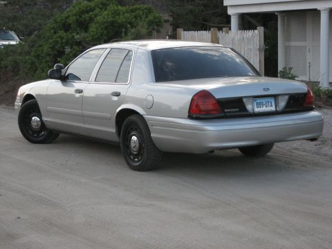 2003 Ford Crown Victoria - This silver 2003 Ford Crown Victoria is seen from the rear quarter angle on a dirt road.