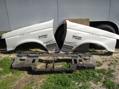 1990 Ford Bronco - White Ford Bronco fenders and grille support are displayed outdoors.