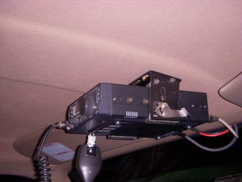 1996 Ford Bronco - A radio is mounted to the ceiling of a vehicle, with a microphone hanging below.