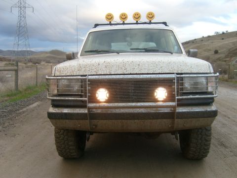 1989 Ford Bronco - Mud-covered 1989 Ford Bronco with custom smiley face lights on the roof rack.