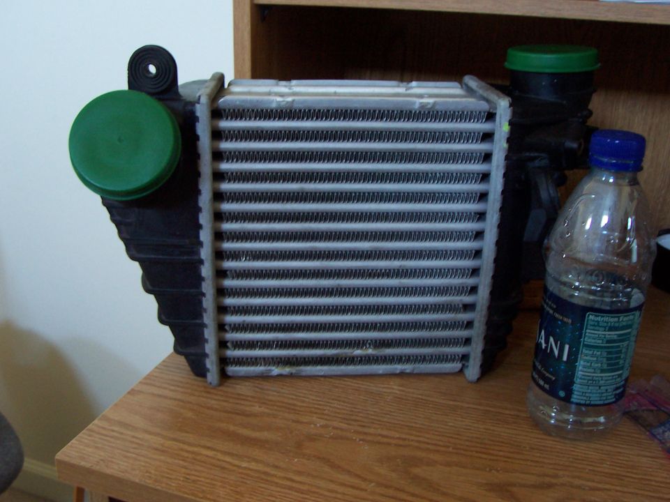 Intercooler with green caps and a water bottle on a wooden surface