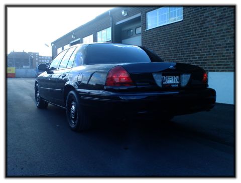 1998 Ford Crown Victoria - Rear view of a black 1998 Ford Crown Victoria, showing its distinctive taillights and license plate.