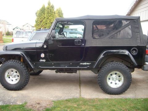 2005 Jeep Wrangler - This black 2005 Jeep Wrangler is shown from the side, its soft top and custom wheels.