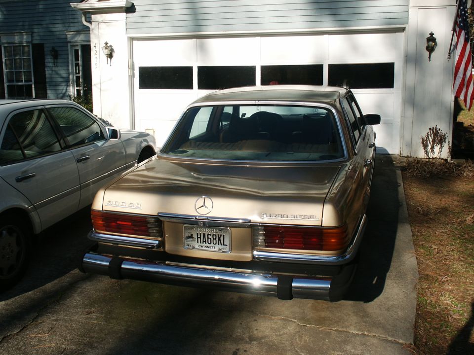 Gold Mercedes-Benz 300 SD Turbo Diesel sedan rear view in driveway