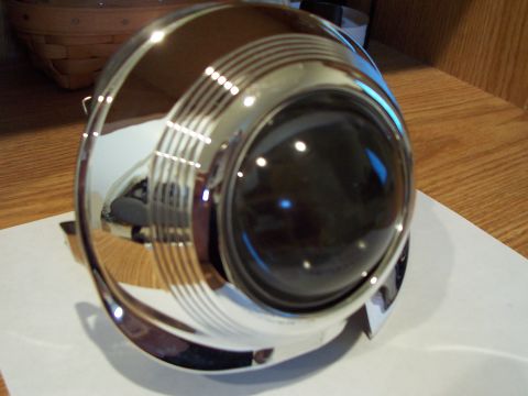 1993 Ford Probe - A close-up of a chrome headlight assembly, likely an aftermarket part, is shown on a wooden surface.