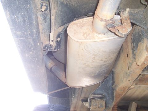 1994 Ford F-150 - Underside view of a vehicle's exhaust system, highlighting the muffler and rusted components.