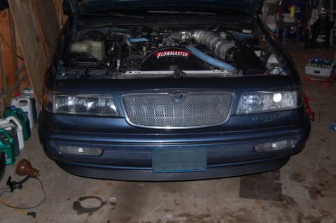 1985 Mercury Grand Marquis - Front view of a blue sedan with its hood open, revealing the engine compartment and a Flowmaster fan.