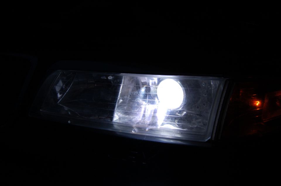 Illuminated white headlight with amber corner lamp at night