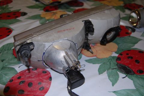 1985 Mercury Grand Marquis - A disassembled car headlight assembly is shown on a table covered with a ladybug-themed cloth.