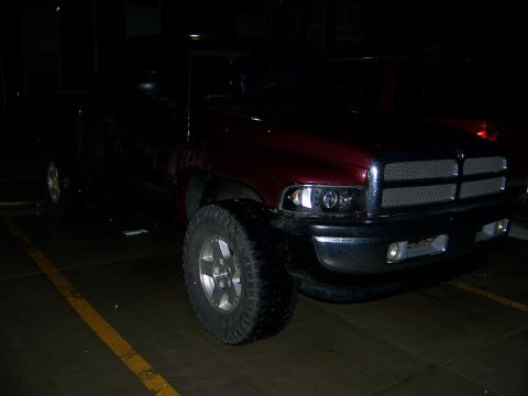 2001 Dodge 1500 - A maroon pickup truck is parked at night, showing its front grille and large tires.