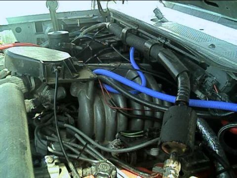 1989 Ford Bronco - Engine bay view down onto a multi-port fuel-injection upper intake manifold with its runners, the distributor with plug wires fanning out a…