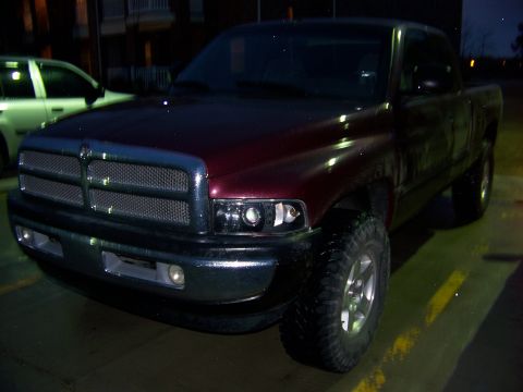 2001 Dodge 1500 - A red Dodge pickup truck is parked in a lot at dusk, with a white SUV visible in the background.