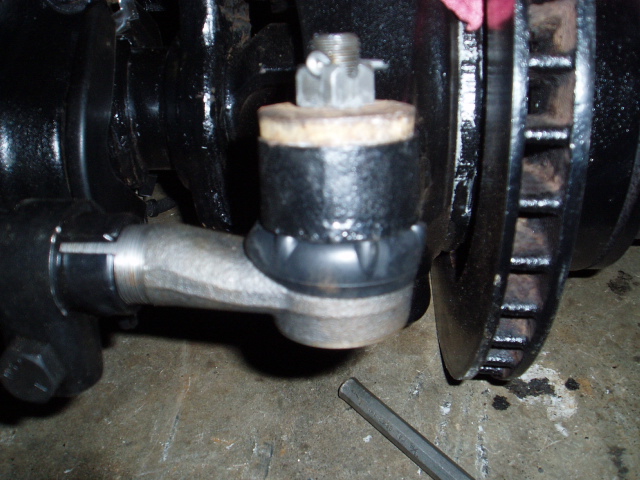Close-up of a vehicle's steering tie rod end connected to the steering knuckle, with a brake rotor visible